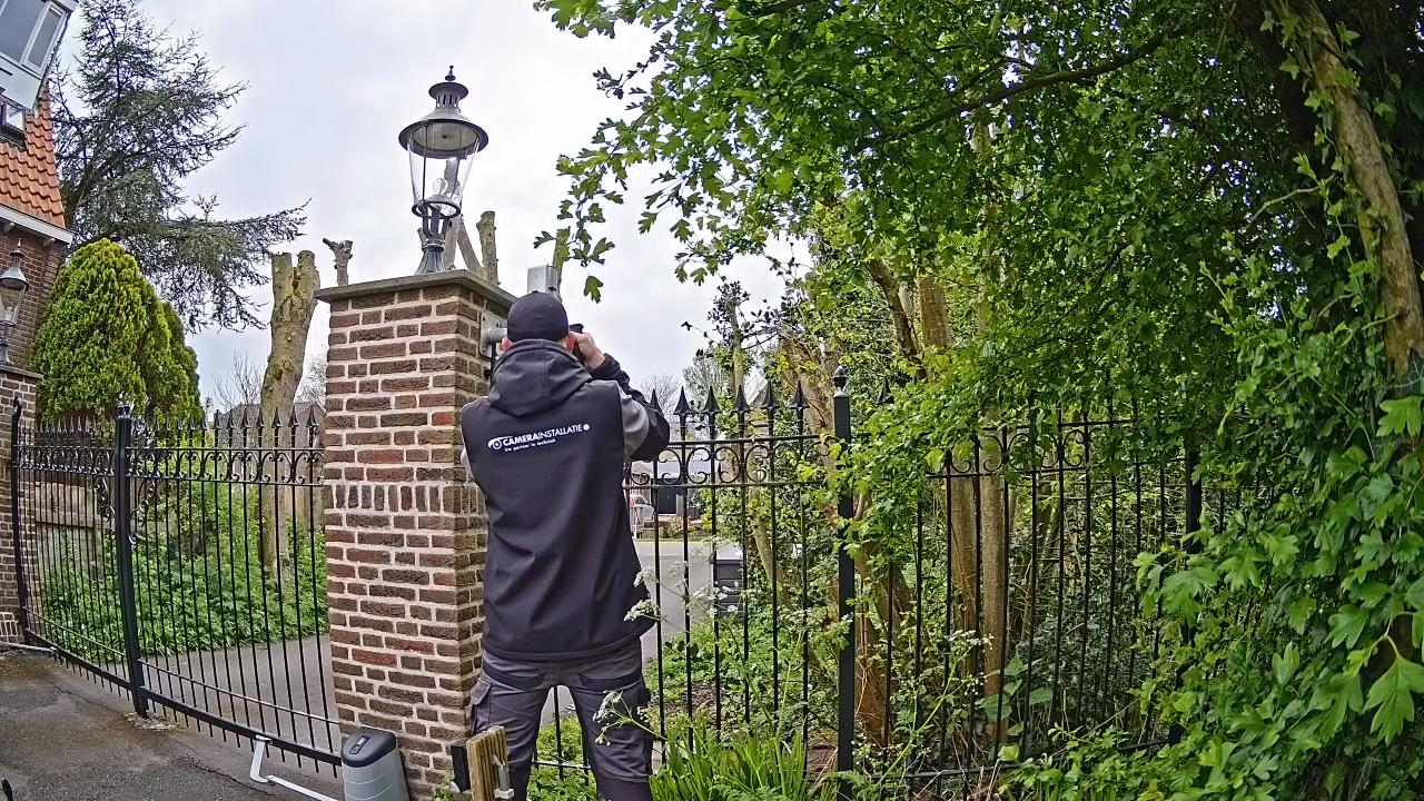 Monteur werkt aan een hekpilaar naast een smeedijzeren toegangshek van een oprit