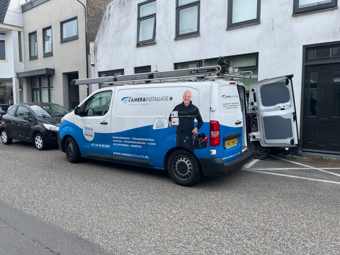 Bedrijfsbus geparkeerd in een smalle straat voor een woning van een klant