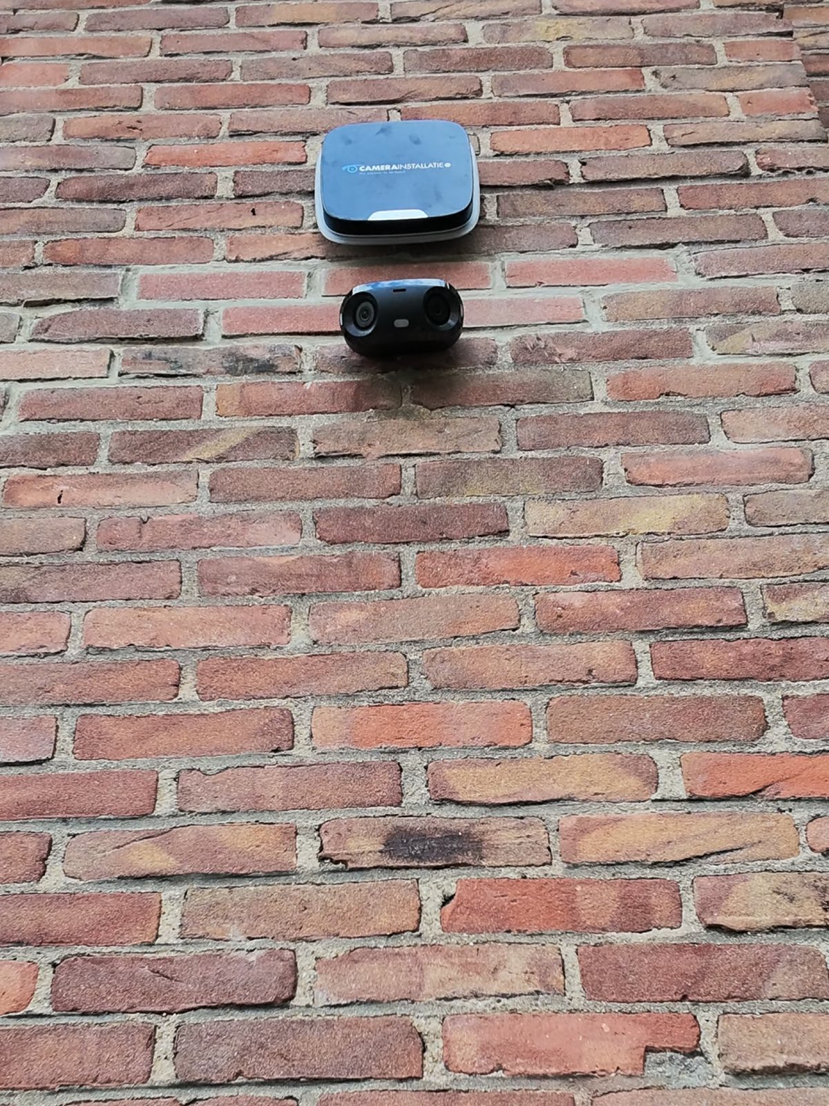 Camera en sirene hoog op een oude bakstenen gevel, buiten handbereik