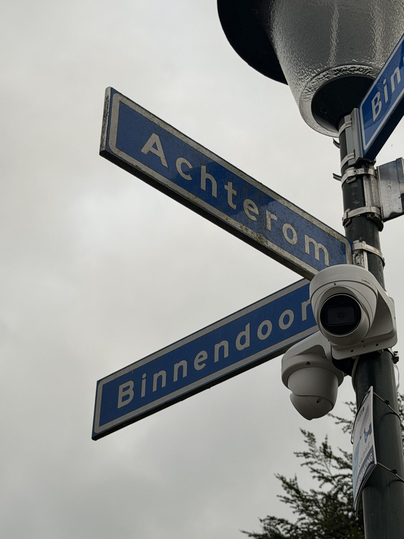 Camera op een paal bij twee straatnaamborden op een dorpshoek