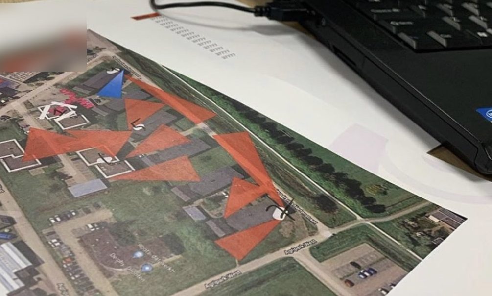 Cameraplan op papier met de zichtlijnen van elke camera op een luchtfoto