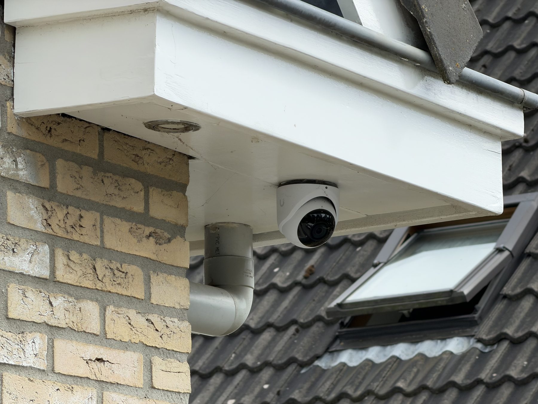 Dome-camera onder de dakrand, netjes naast de regenpijp geplaatst