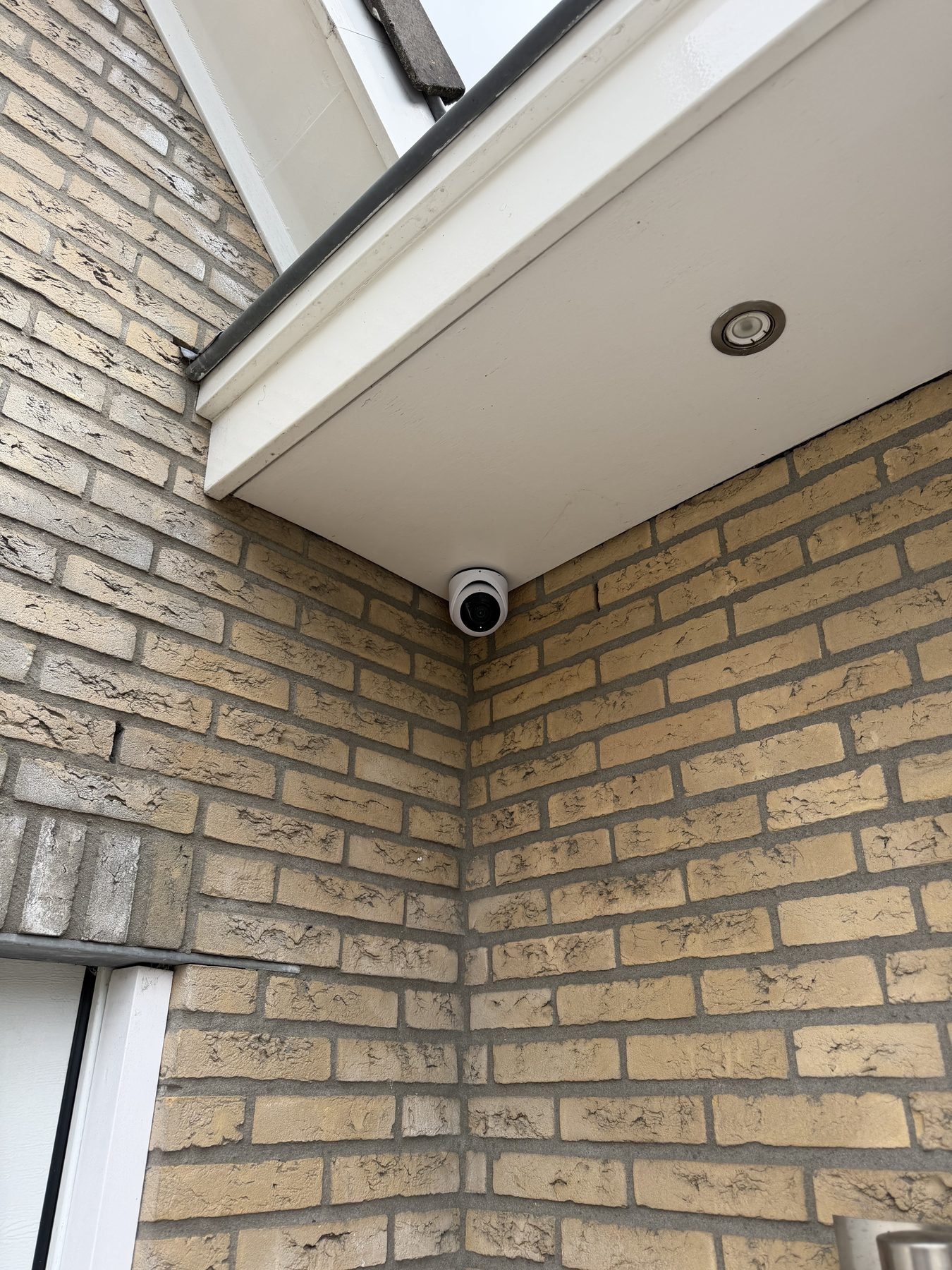 Kleine dome-camera weggewerkt onder de dakrand van een woning