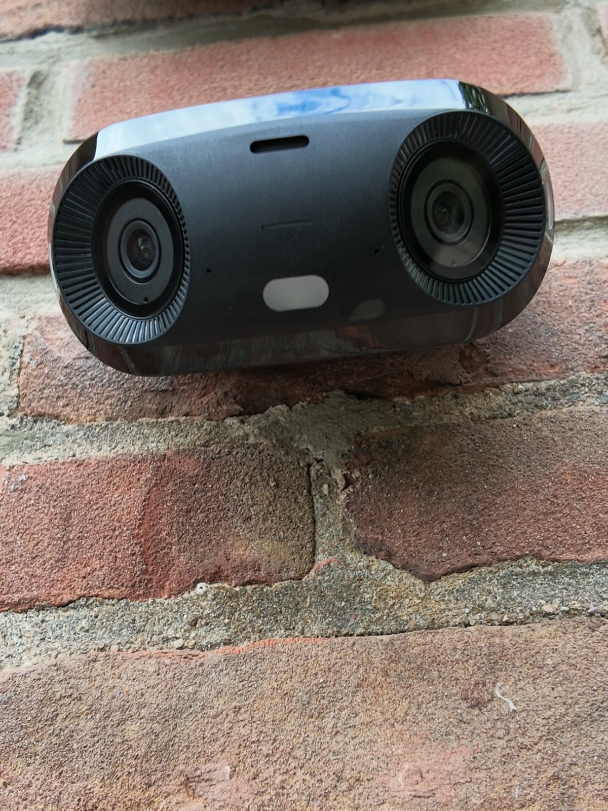 Close-up van een camera met twee lenzen op een oude bakstenen gevel