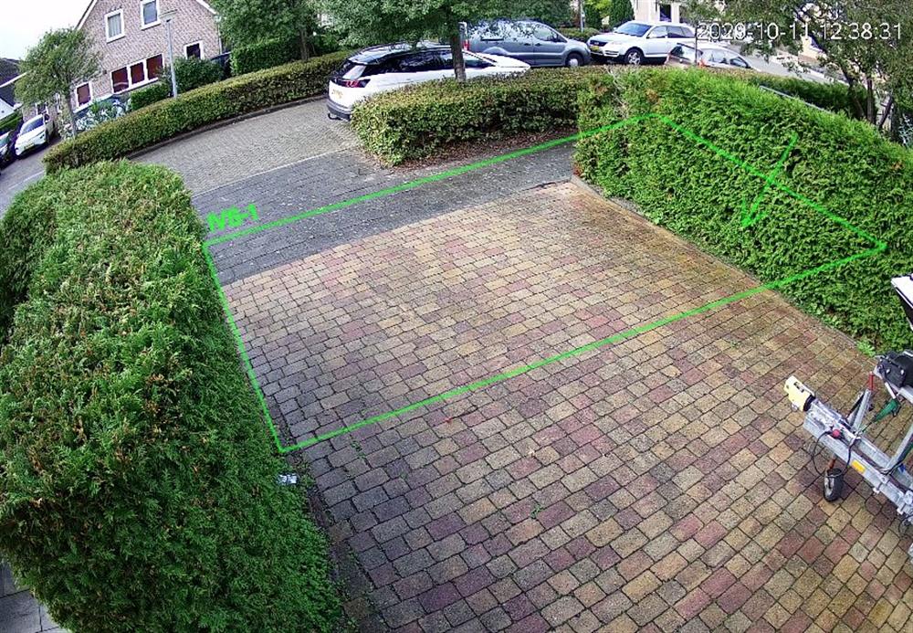 Echt camerabeeld van een oprit met een ingetekende groene detectiezone en de tijdstempel van de camera.