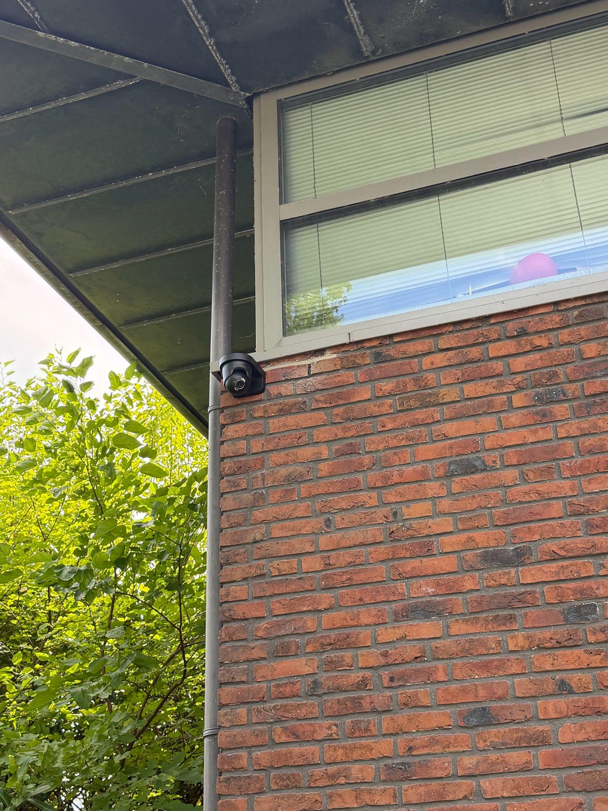 IP-camera onder het dakoverstek van een woning, langs de regenpijp