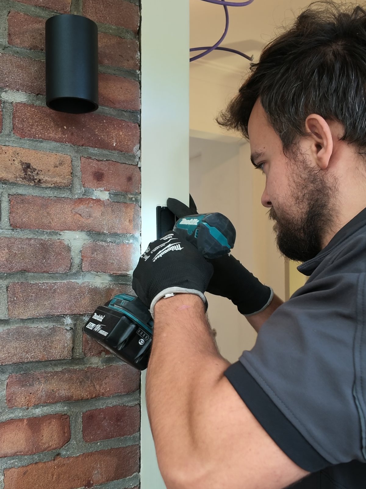 Monteur van CameraInstallatie.nl boort de beugel vast op de gevel van een woning