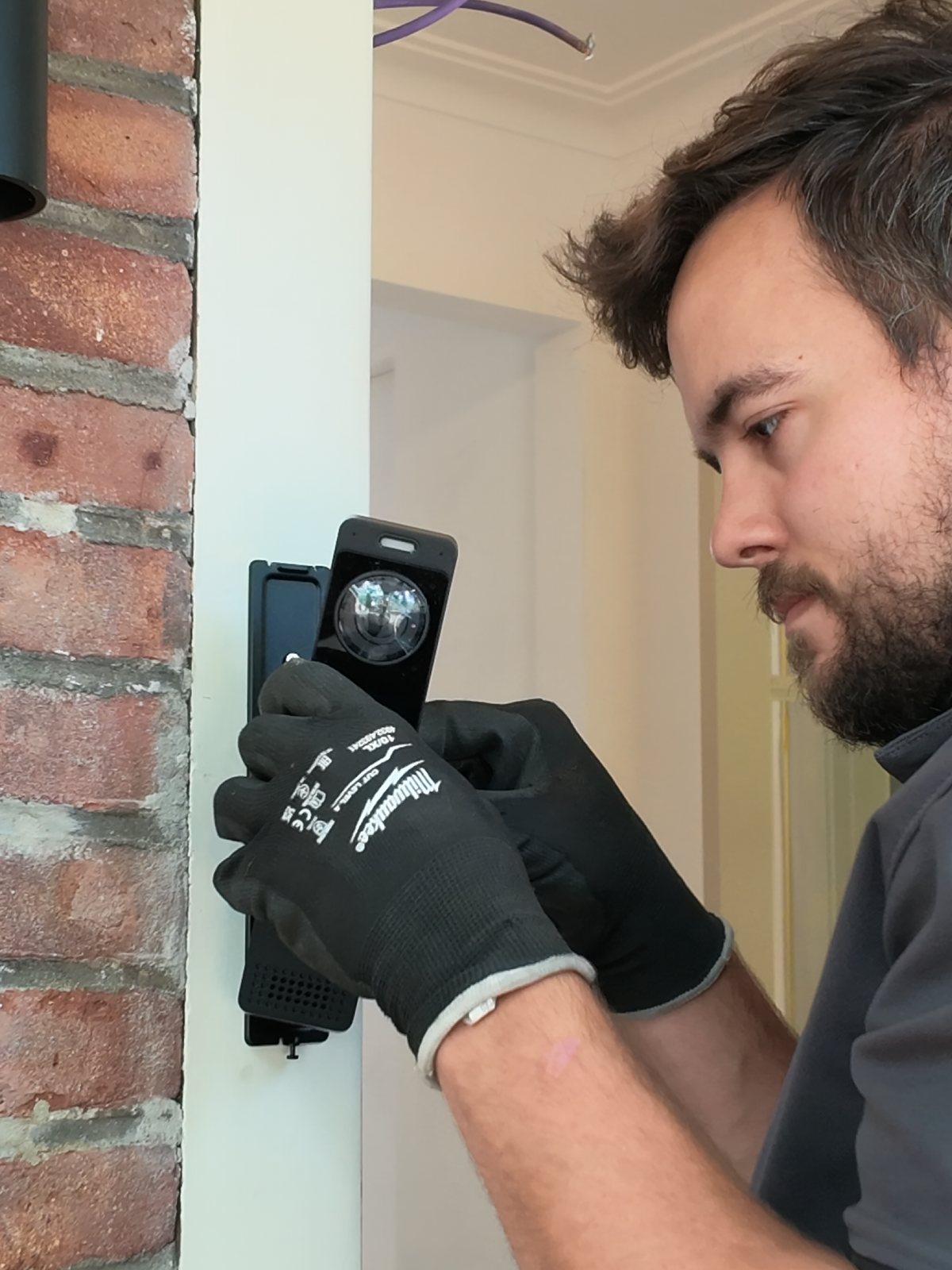 Monteur hangt een deurbelcamera met twee lenzen op naast de voordeur