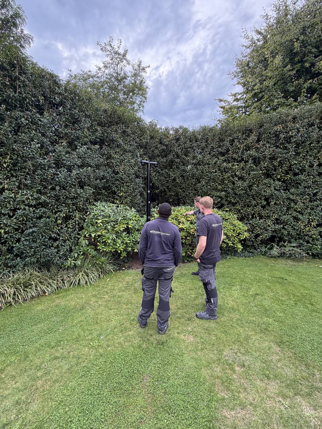 Twee monteurs van CameraInstallatie bij de geplaatste cameramast achter in de tuin