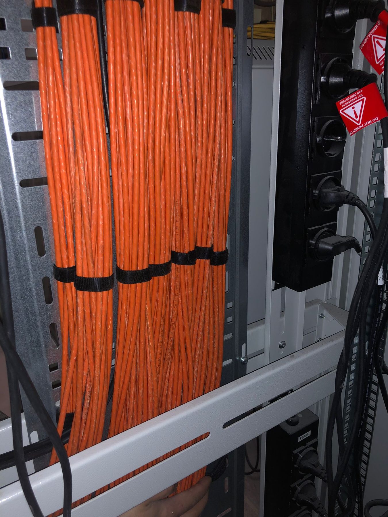Bundels oranje netwerkkabel netjes gebundeld in een rack
