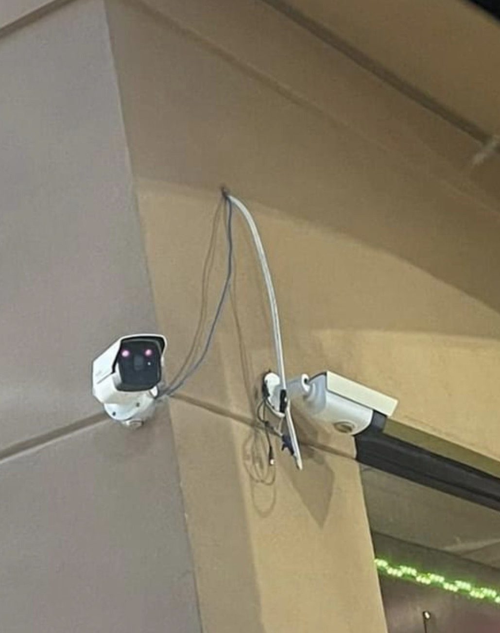 Twee camera's met zichtbare kabellussen tegen een gestucte gevel