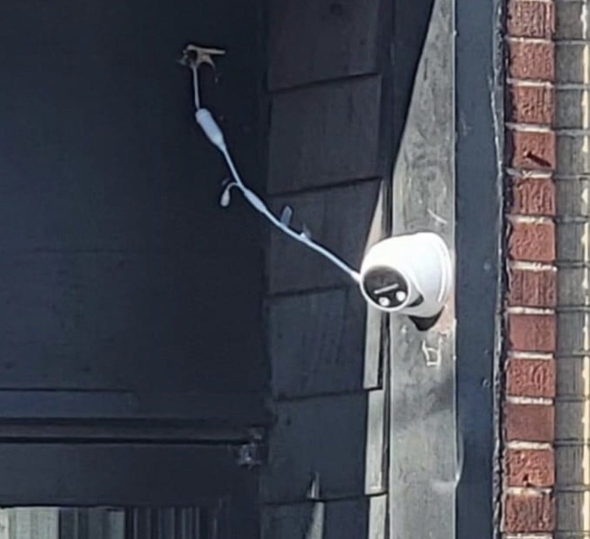 Witte kabel dwars over een zwarte gevel naar een losse camera