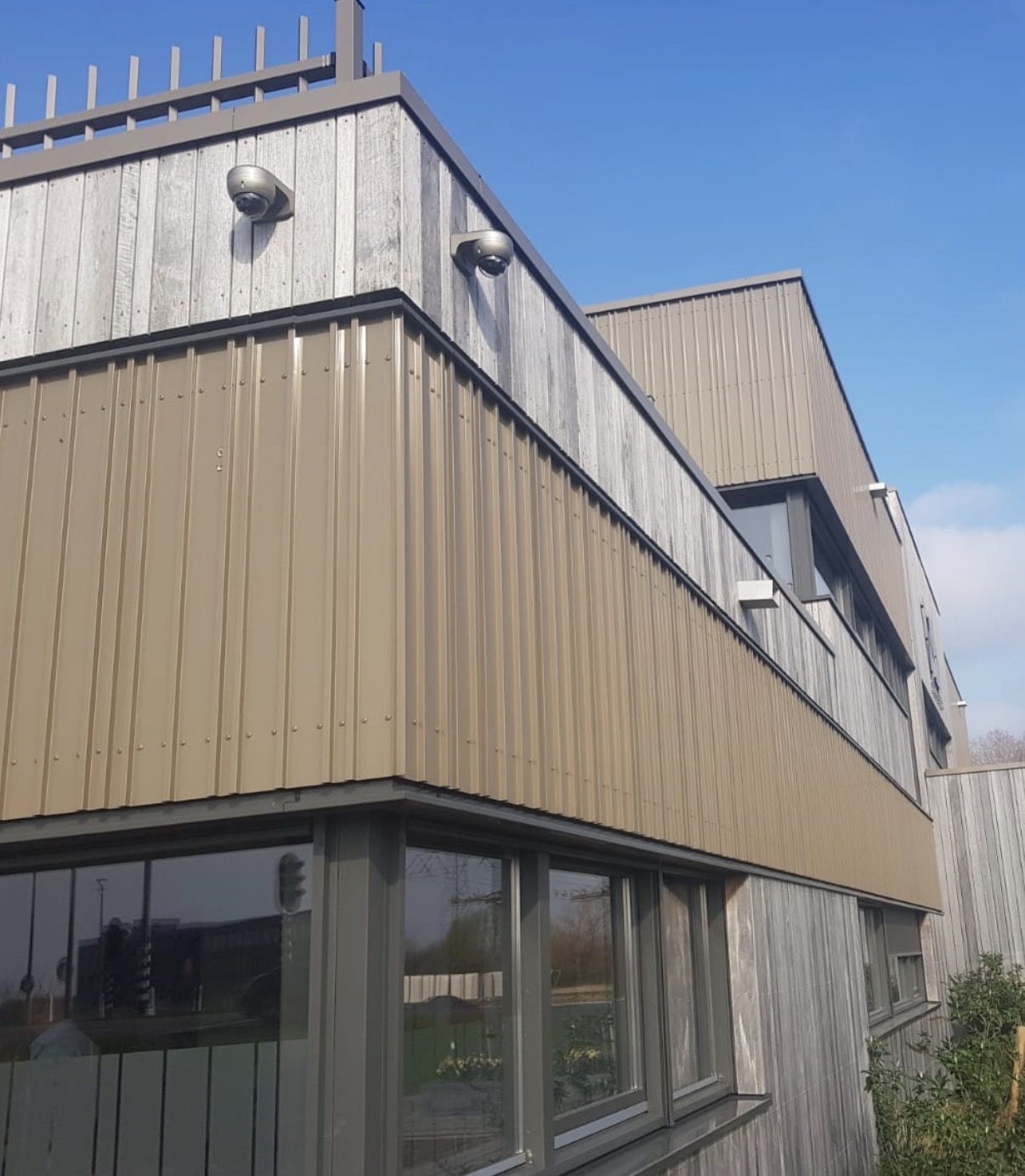 Twee dome-camera's op de hoek van een bedrijfspand met houten gevel