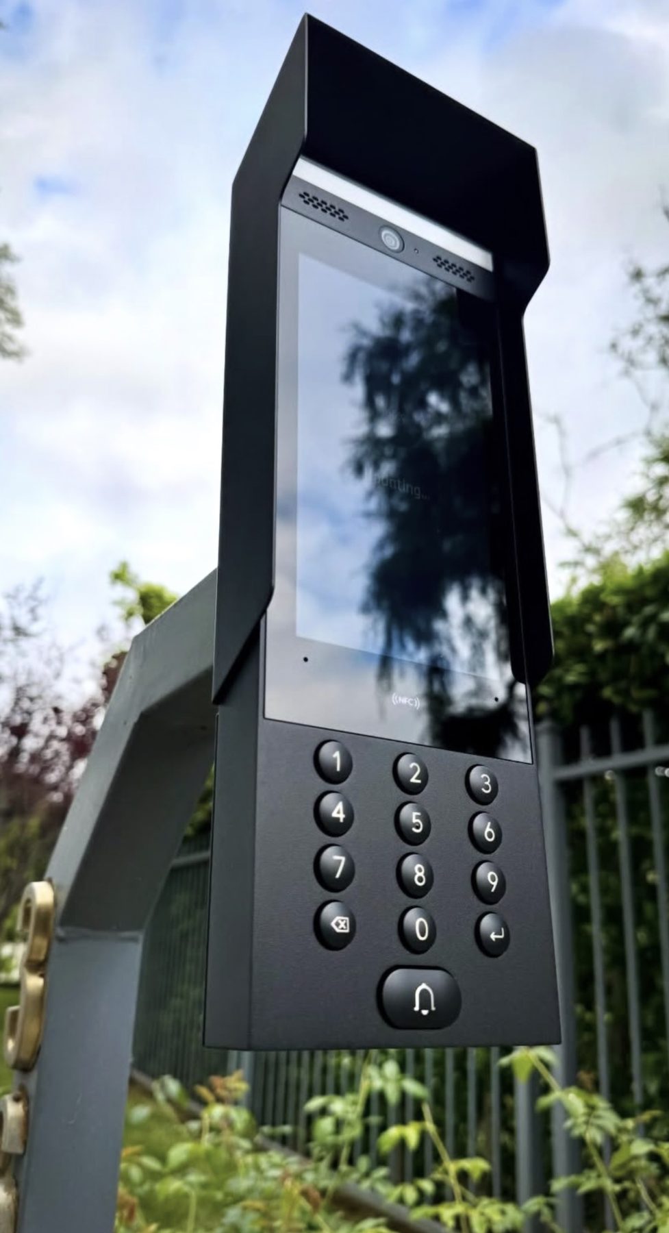 Video-intercom met scherm en toetsenbord op een paal bij het hek