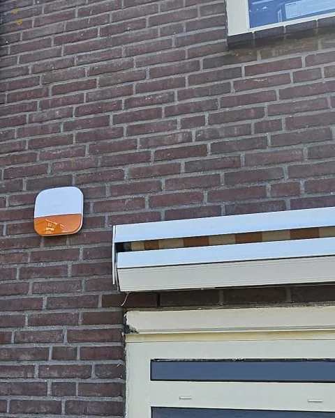 Buitensirene met oranje flitser aan de gevel van een woonhuis