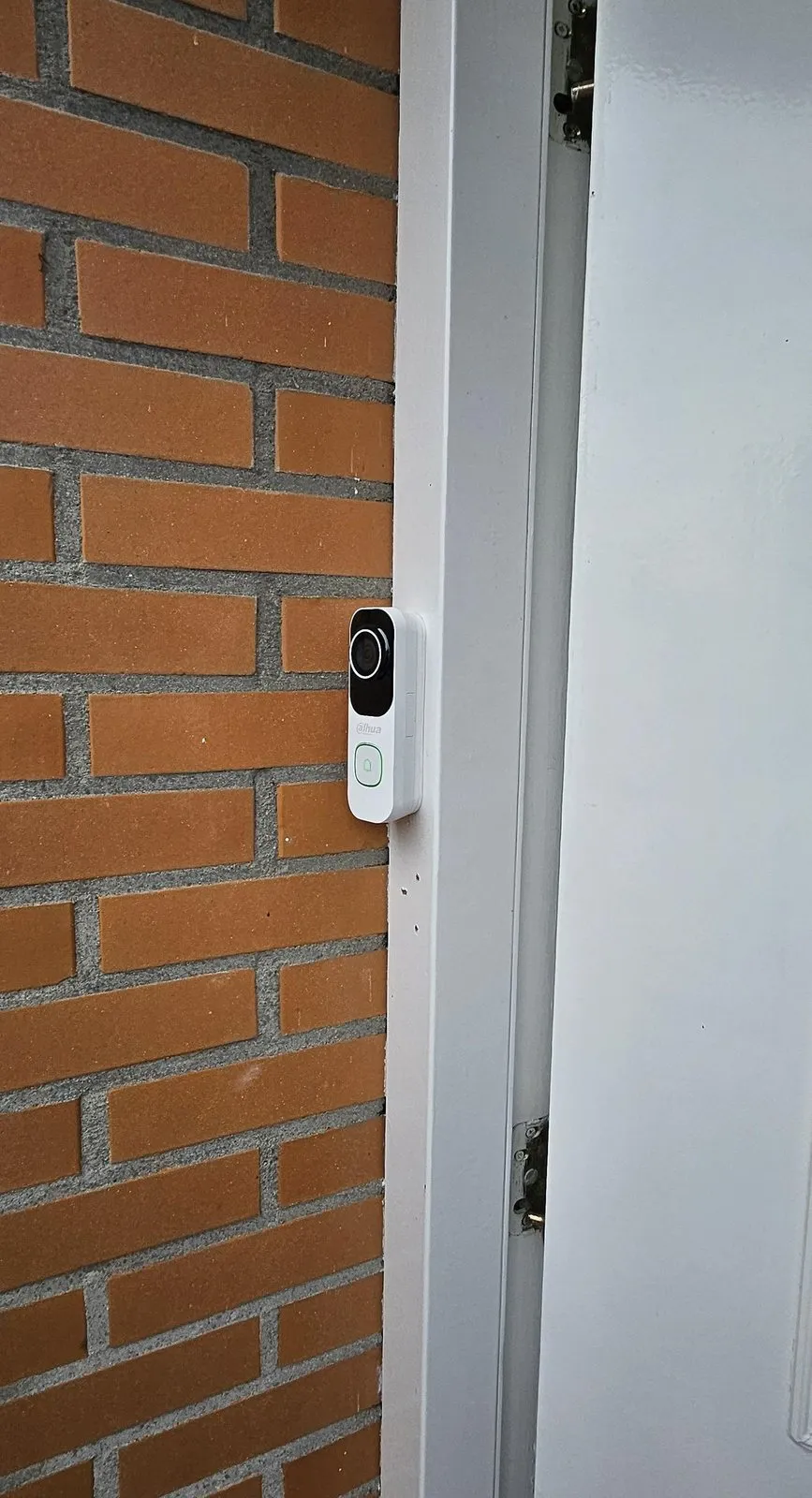 Witte Dahua-videodeurbel op het kozijn naast de voordeur in Maassluis