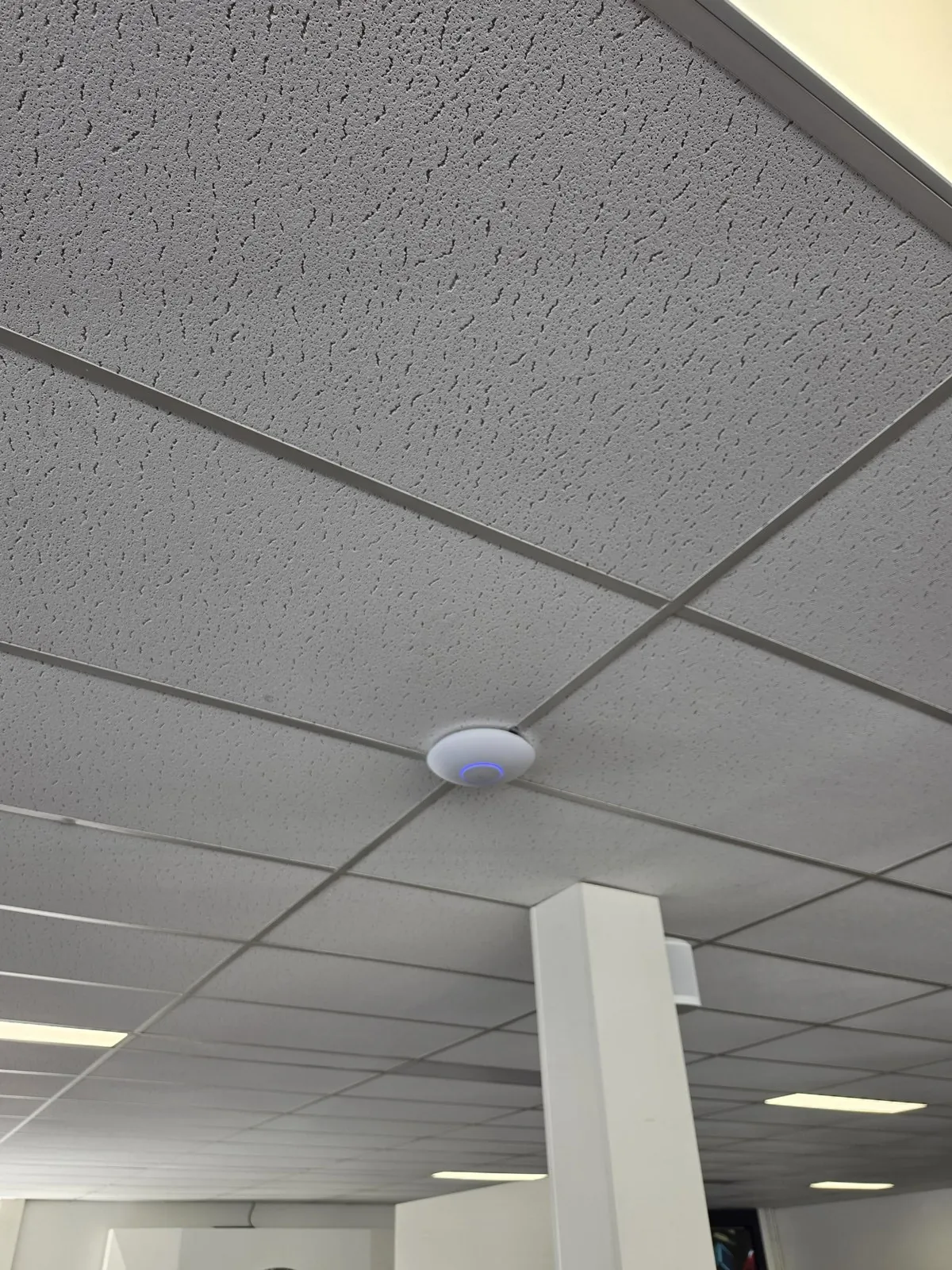 Rond wit access point tussen de systeemplaten bij een autobedrijf in Den Haag