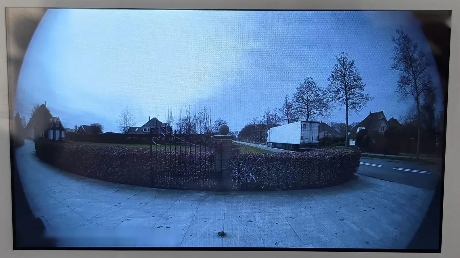 Groothoekbeeld op de binnenpost in Heerhugowaard met bestrating, hek in de heg en de weg