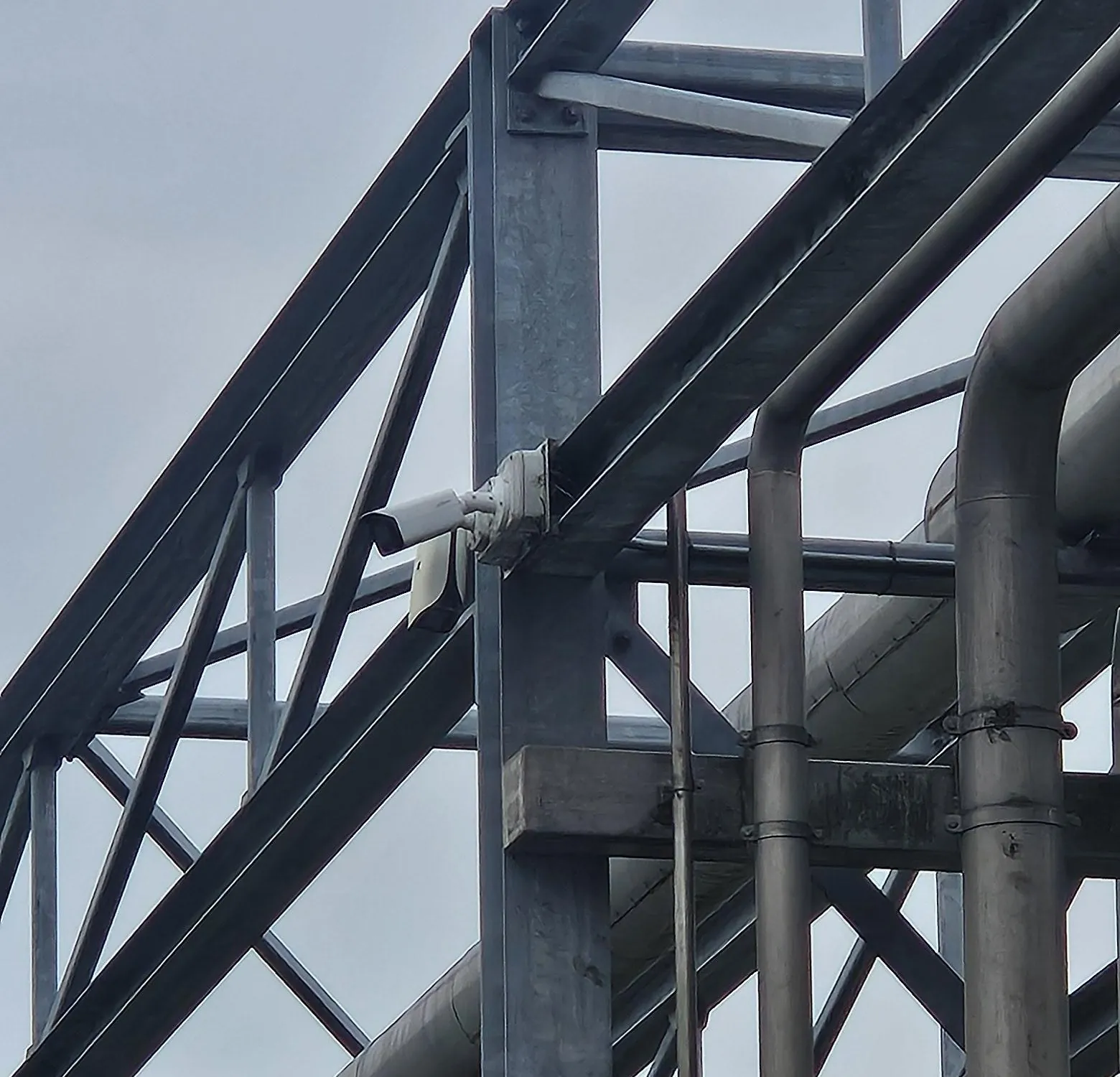 Bulletcamera aan de staander van een pijpbrug op een productieterrein in Amsterdam