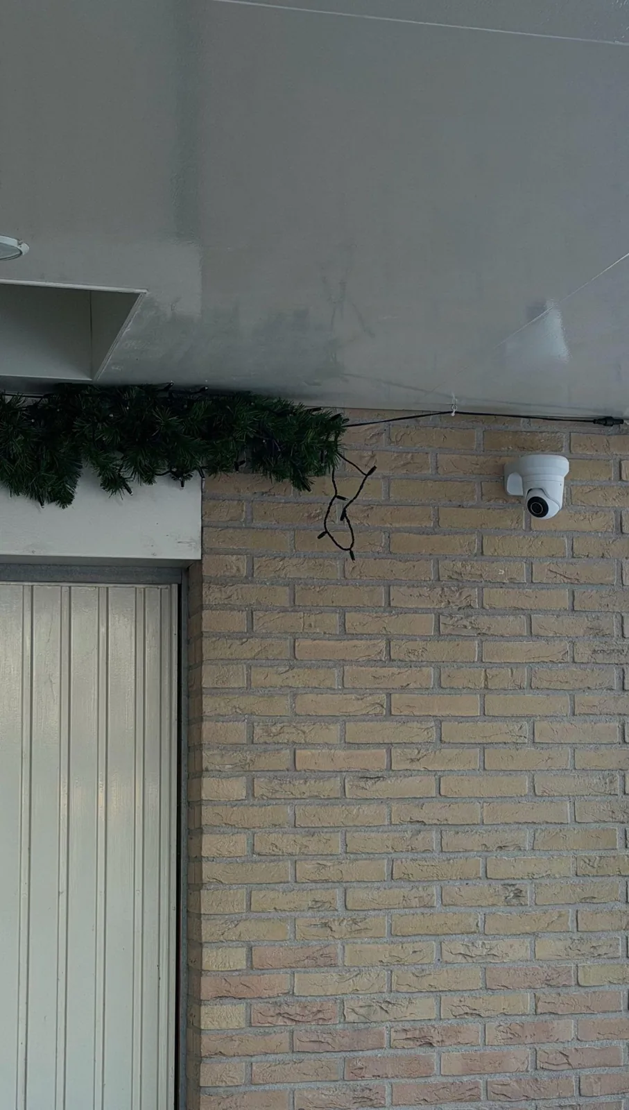 Witte camera naast de garagedeur onder de overkapping, sneeuw rond de woning in Oudewater