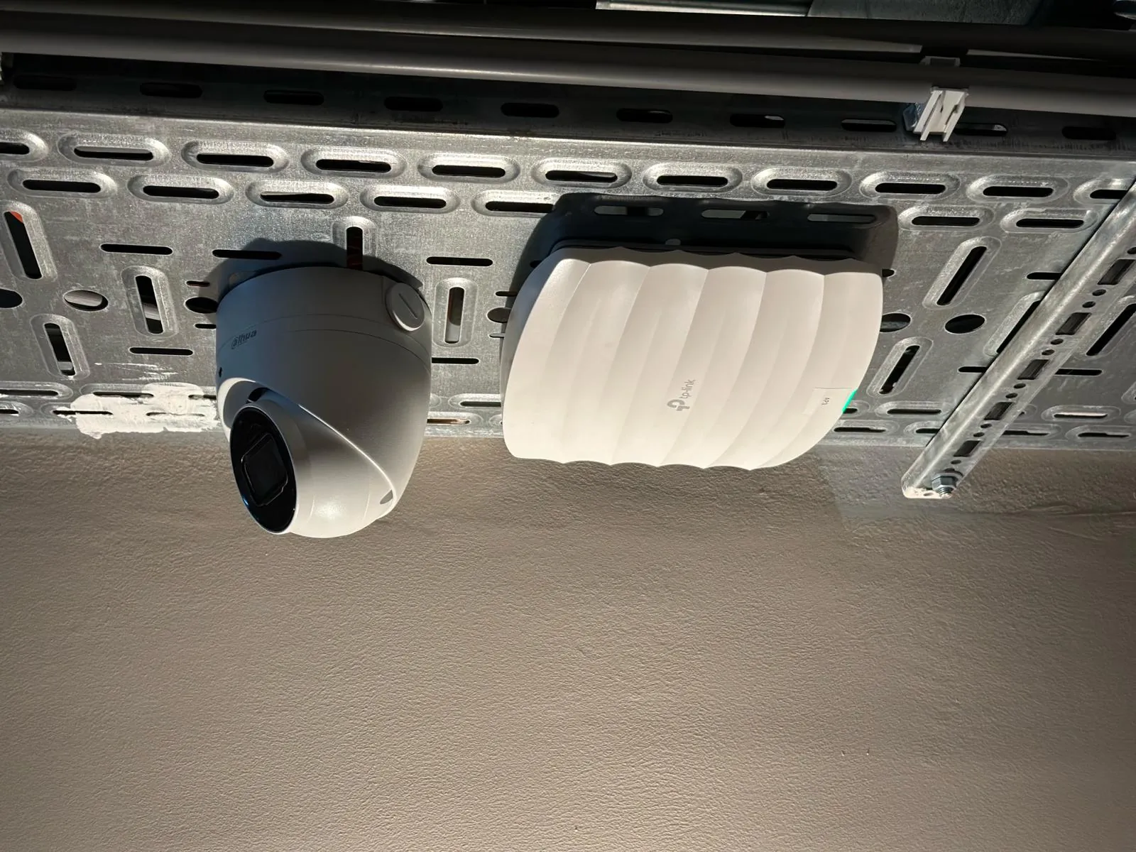 Camera en accesspoint naast elkaar aan een kabelgoot in de gang van een hotel in Amsterdam