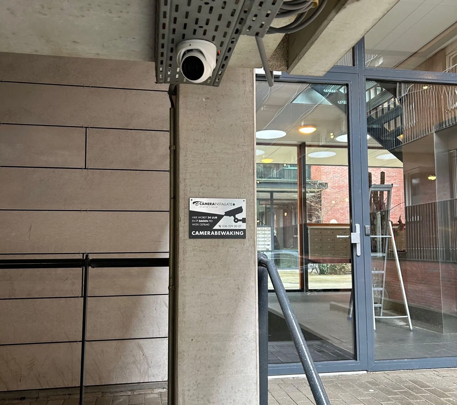 Camera onder de goot bij de entree van het complex in Amsterdam, met een camerabordje