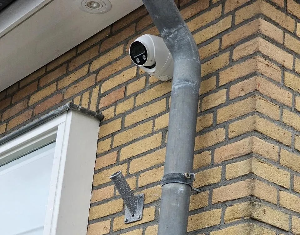 Witte camera op de dakhoek van een gele gevel in Wilnis, bij de zinken afvoer