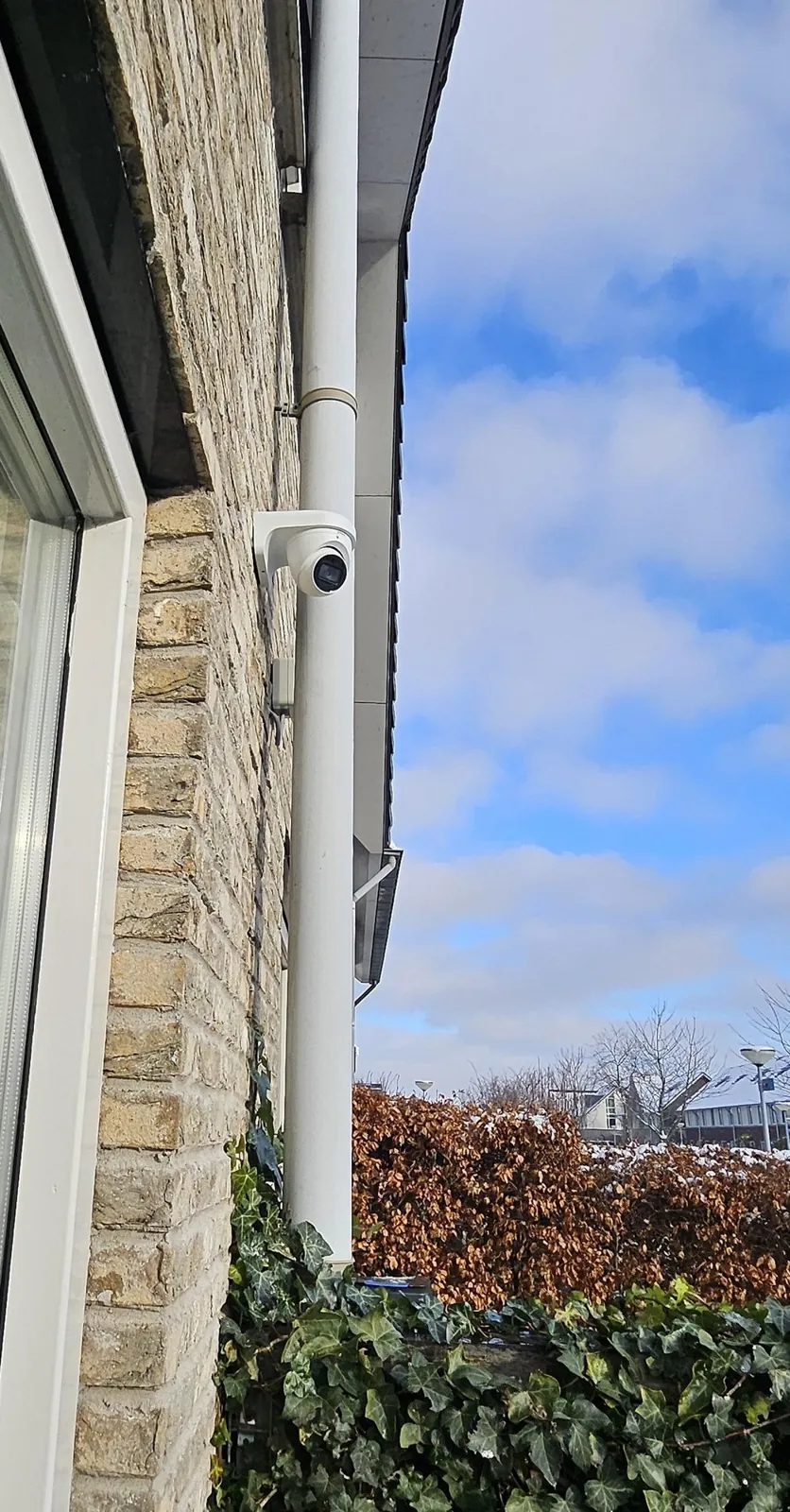 Witte camera hoog naast de regenpijp op een bakstenen gevel in Almere