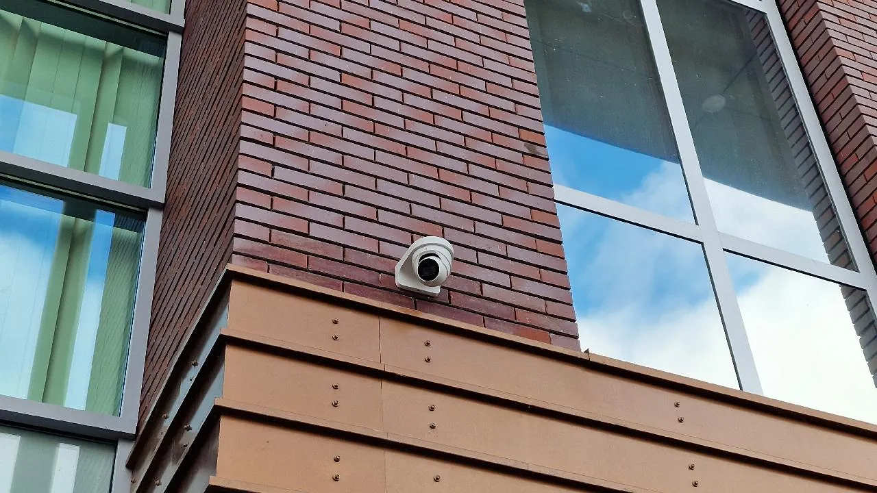 Camera op een steun tegen de bakstenen gevel van een school in Almere