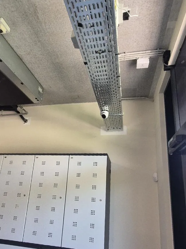 Camera naast een kabelgoot in de techniekruimte van een hotel, tegen het plafond