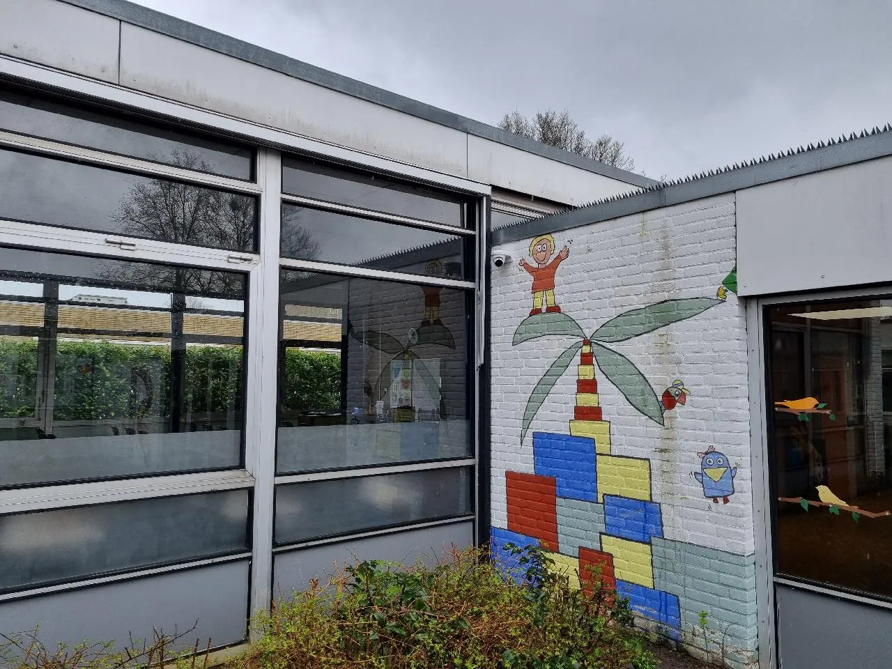 Camera op de witte gevel van een school in Zwolle, naast een muurschildering