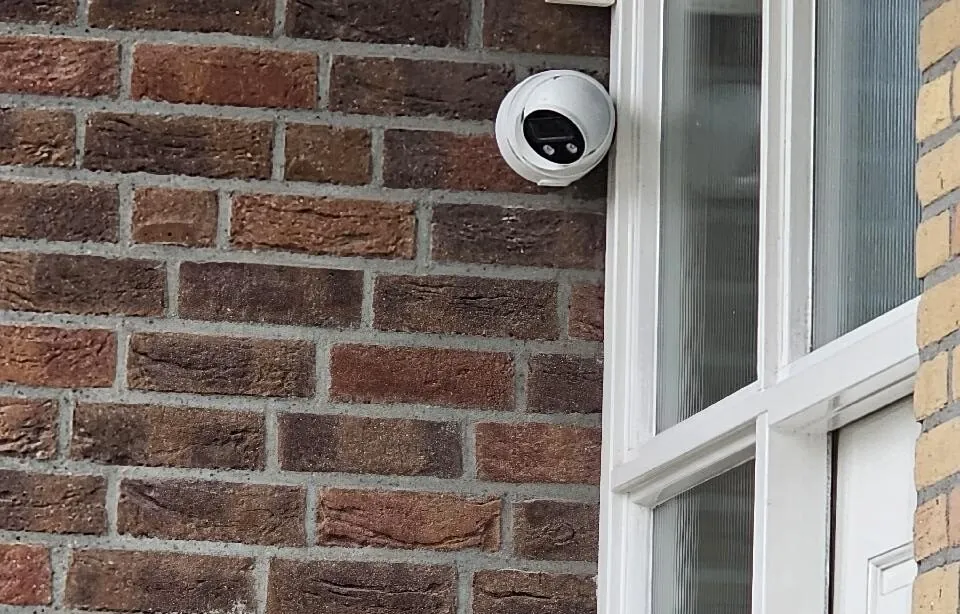 Witte camera op een roodbruine bakstenen gevel naast de voordeur van een woning in Wilnis