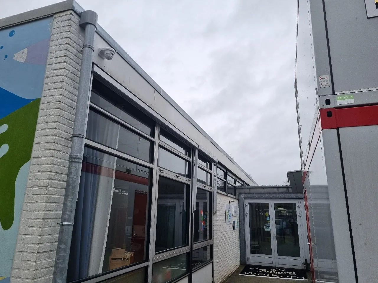 Camera op de gevelhoek bij de glazen ingang van een school in Zwolle