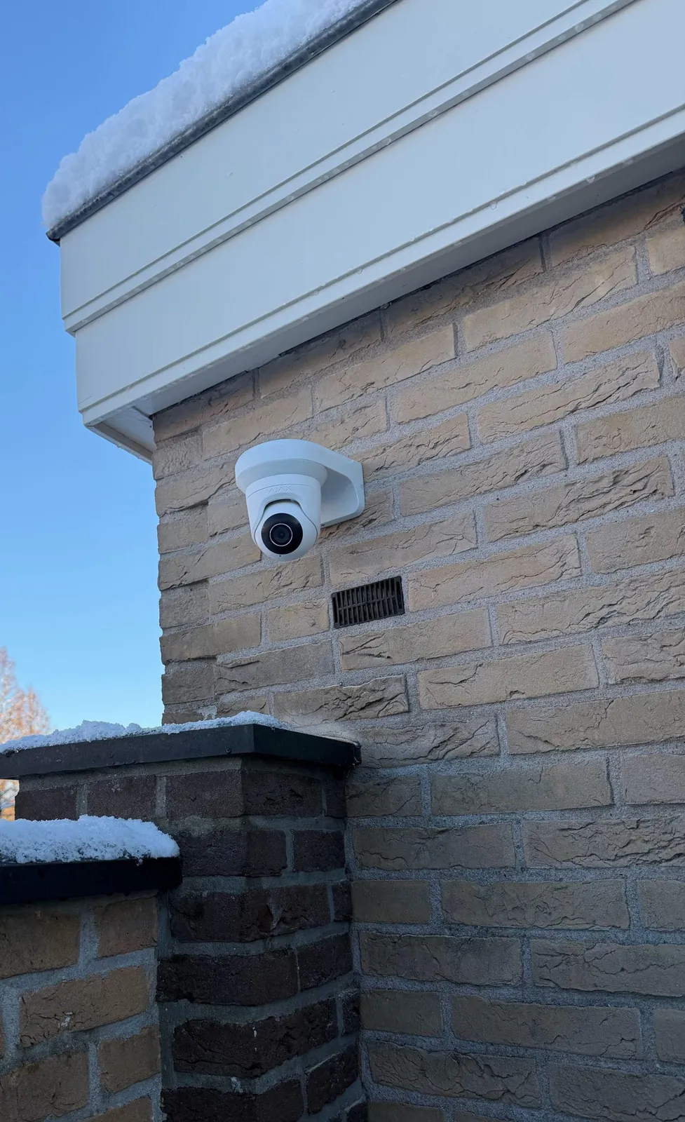 Witte camera onder de dakrand van de zijgevel in Oudewater, met besneeuwde tuinmuur