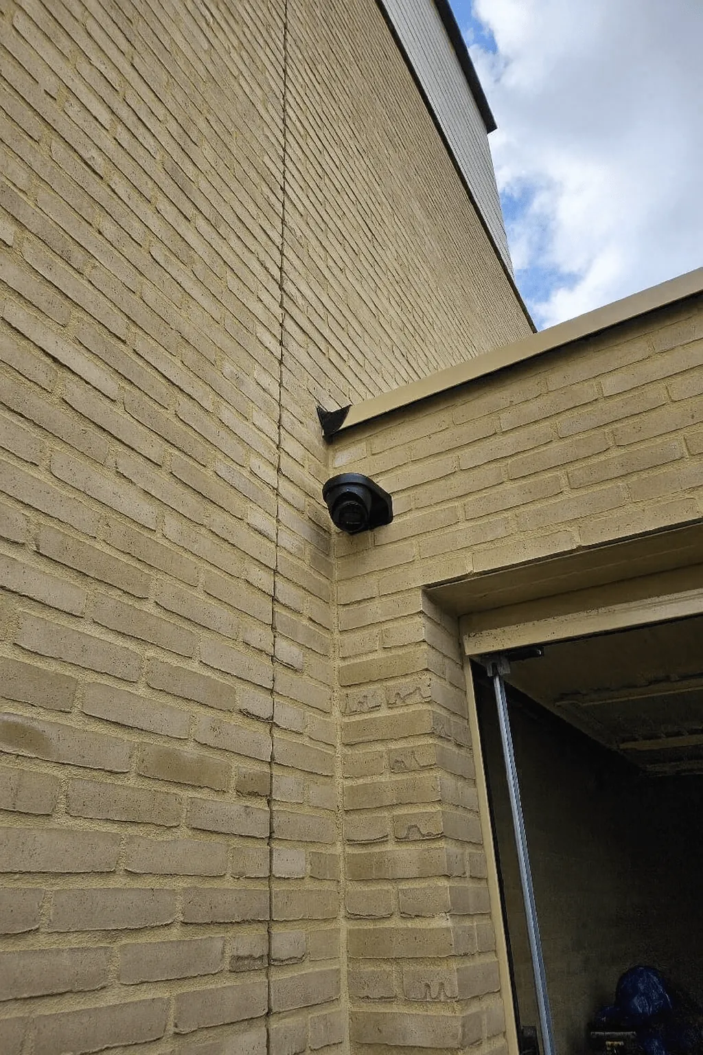 Zwarte Dahua-dome hoog op de gevelhoek, zonder kabel in zicht