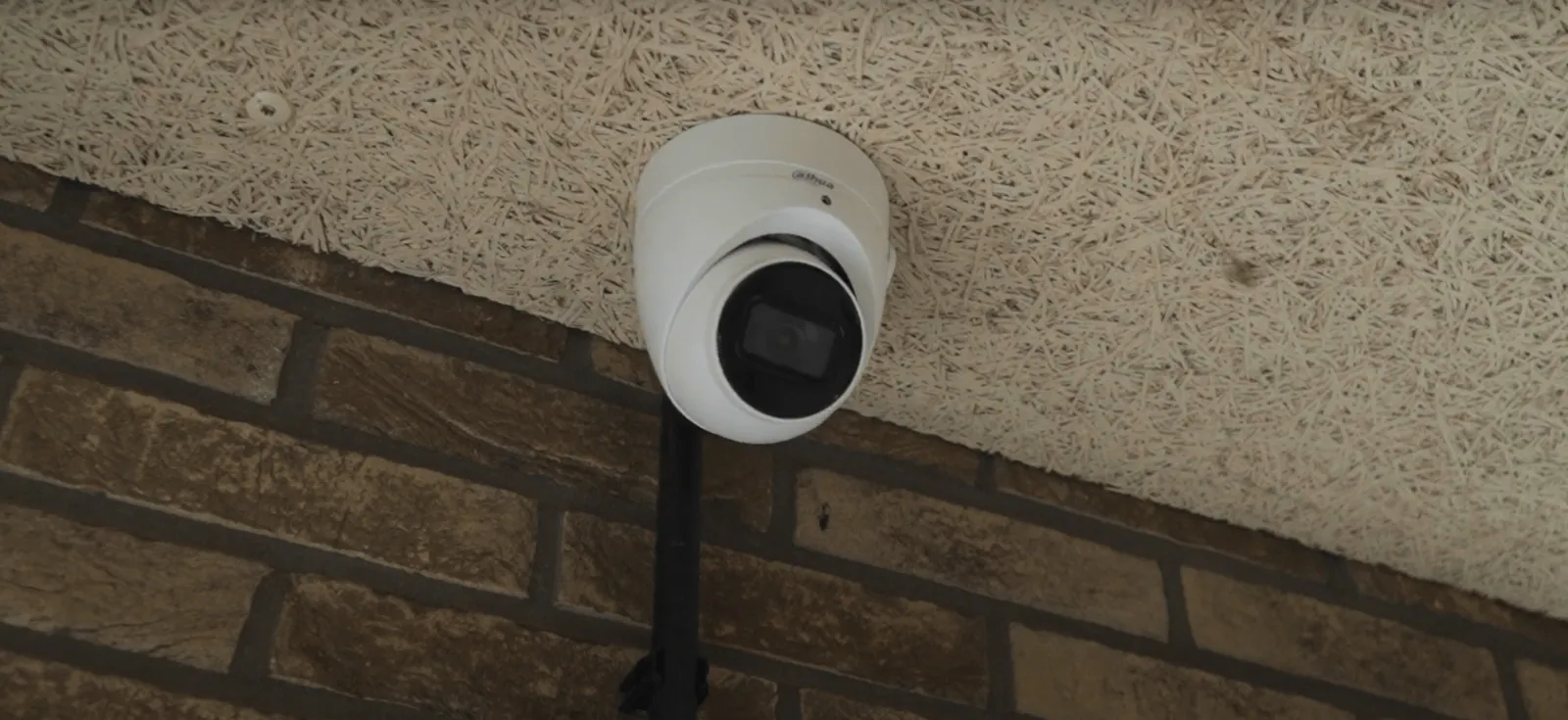 Witte Dahua Starlight-camera op een beugel tegen de bakstenen wand van de parkeergarage van een VvE in Haarlem