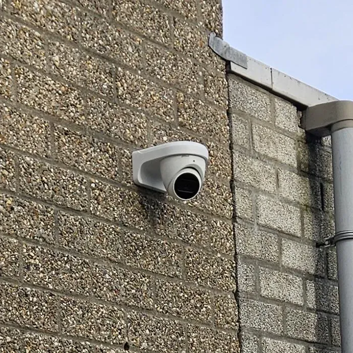 Close-up van de 8 MP Dahua-turret op grindsteen naast de regenpijp in Voorburg