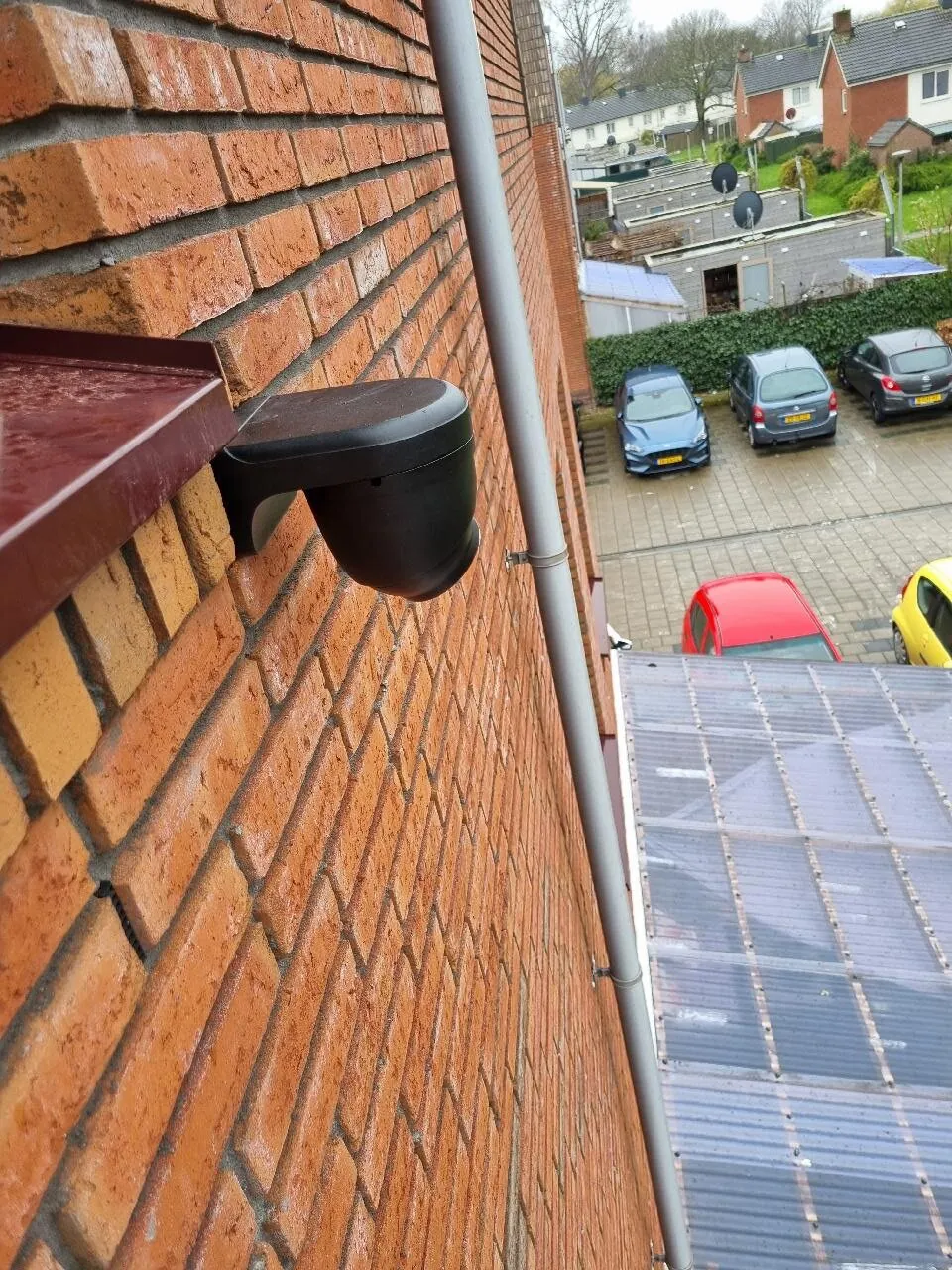 Zwarte Dahua-turretcamera hoog op een bakstenen gevel in Arnhem, gericht op een parkeerplaats