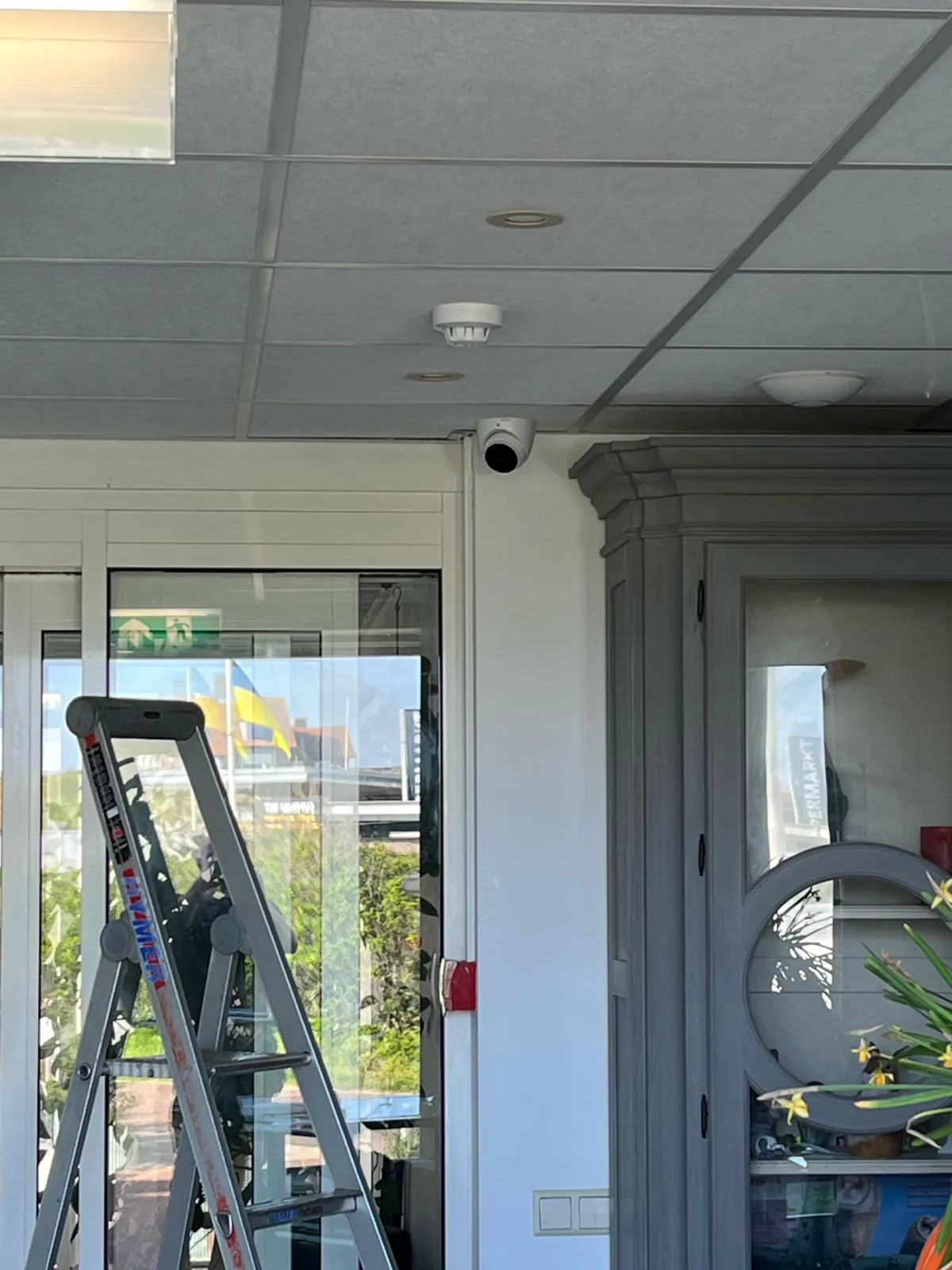 Witte dome boven de schuifdeur bij de hotelentree in Bergen aan Zee, met een trap ervoor