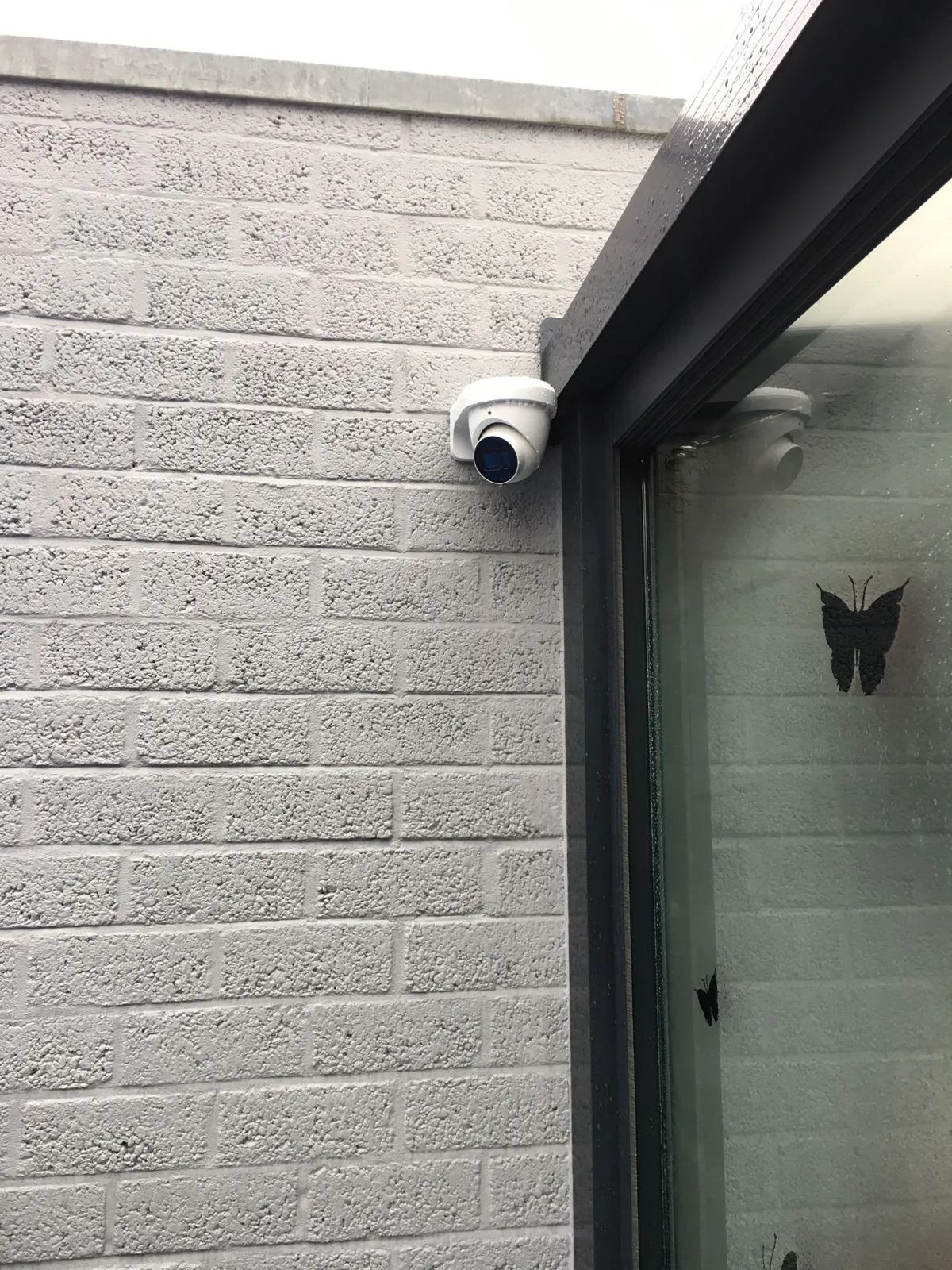 Witte domecamera op de grijze gevel naast de schuifpui van een chalet in Biddinghuizen
