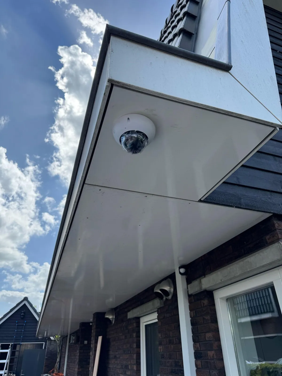 Witte domecamera onder het overstek van een bakstenen woning in Blaricum