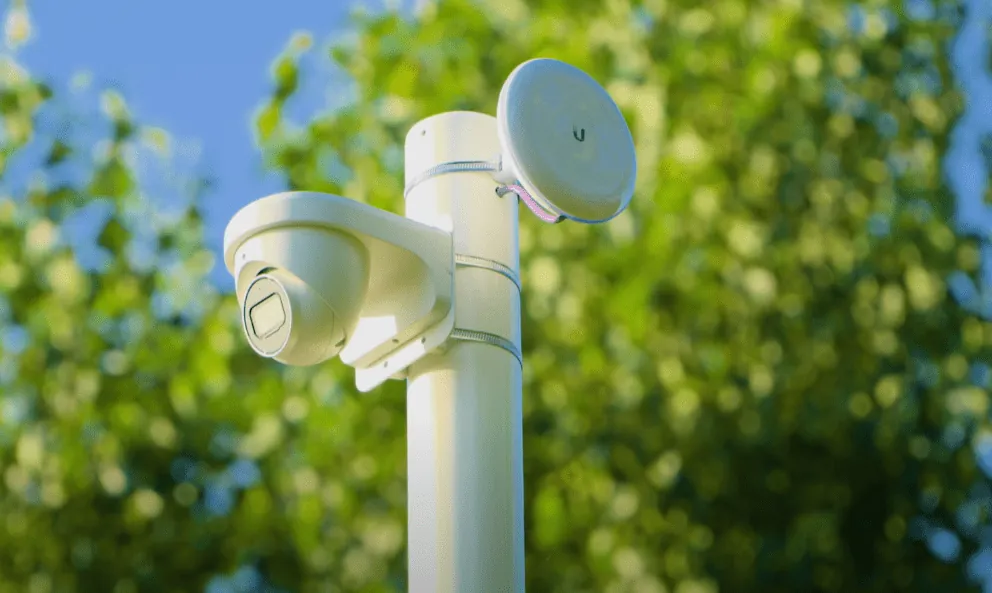 Witte dome-camera en een straalzender samen op een paal tussen de bomen van de Keukenhof in Lisse