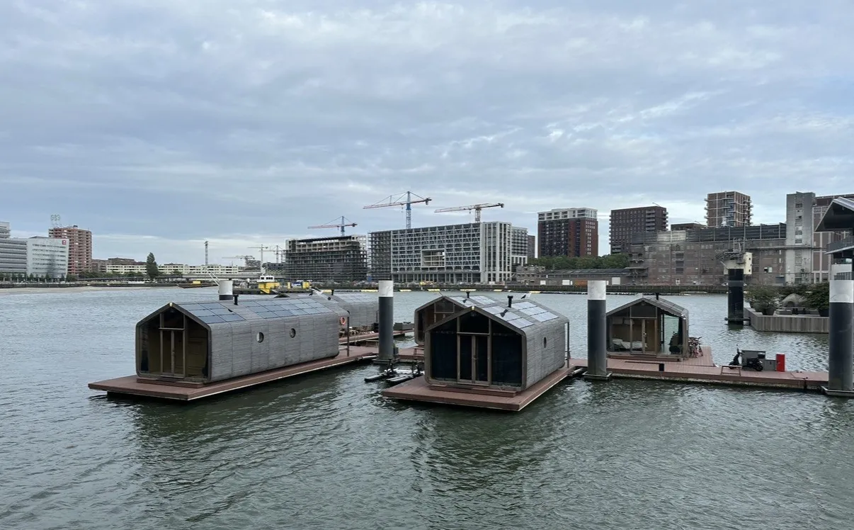 Drijvende hotelkamers op het water in Rotterdam, met de skyline erachter