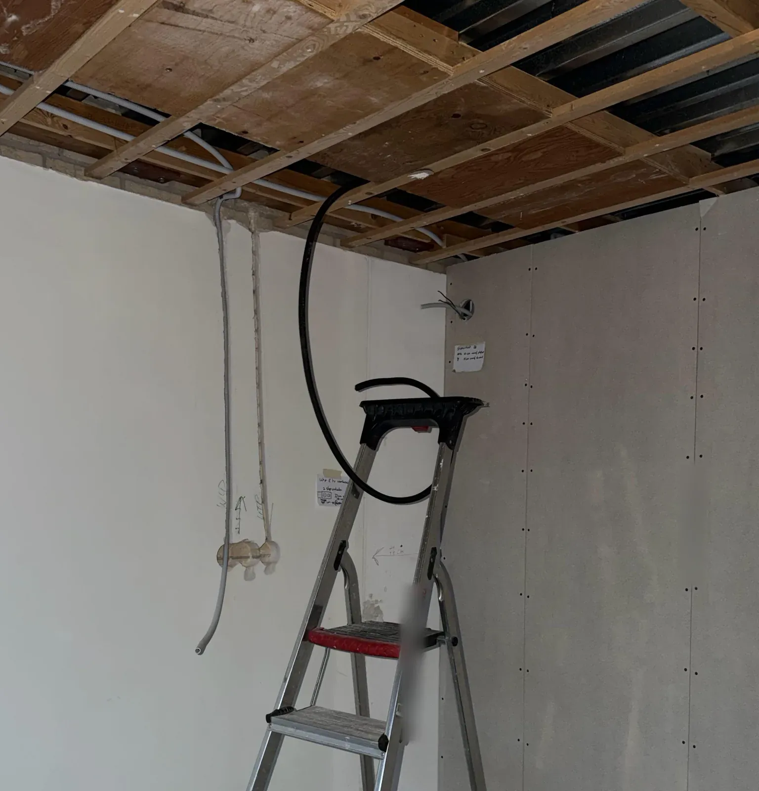 Kamer met open plafond tijdens de verbouwing in Almere, flexbuizen lopen naar de inbouwdozen