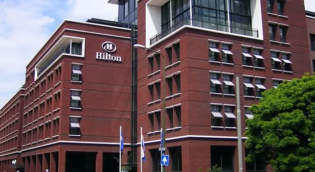 Bakstenen hotelgevel met het Hilton-logo boven de zonneschermen, Den Haag
