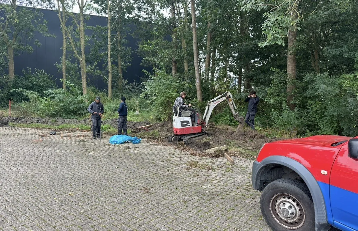 Langs de rand van het bos wordt een sleuf gegraven voor de kabel naar een buitenkast