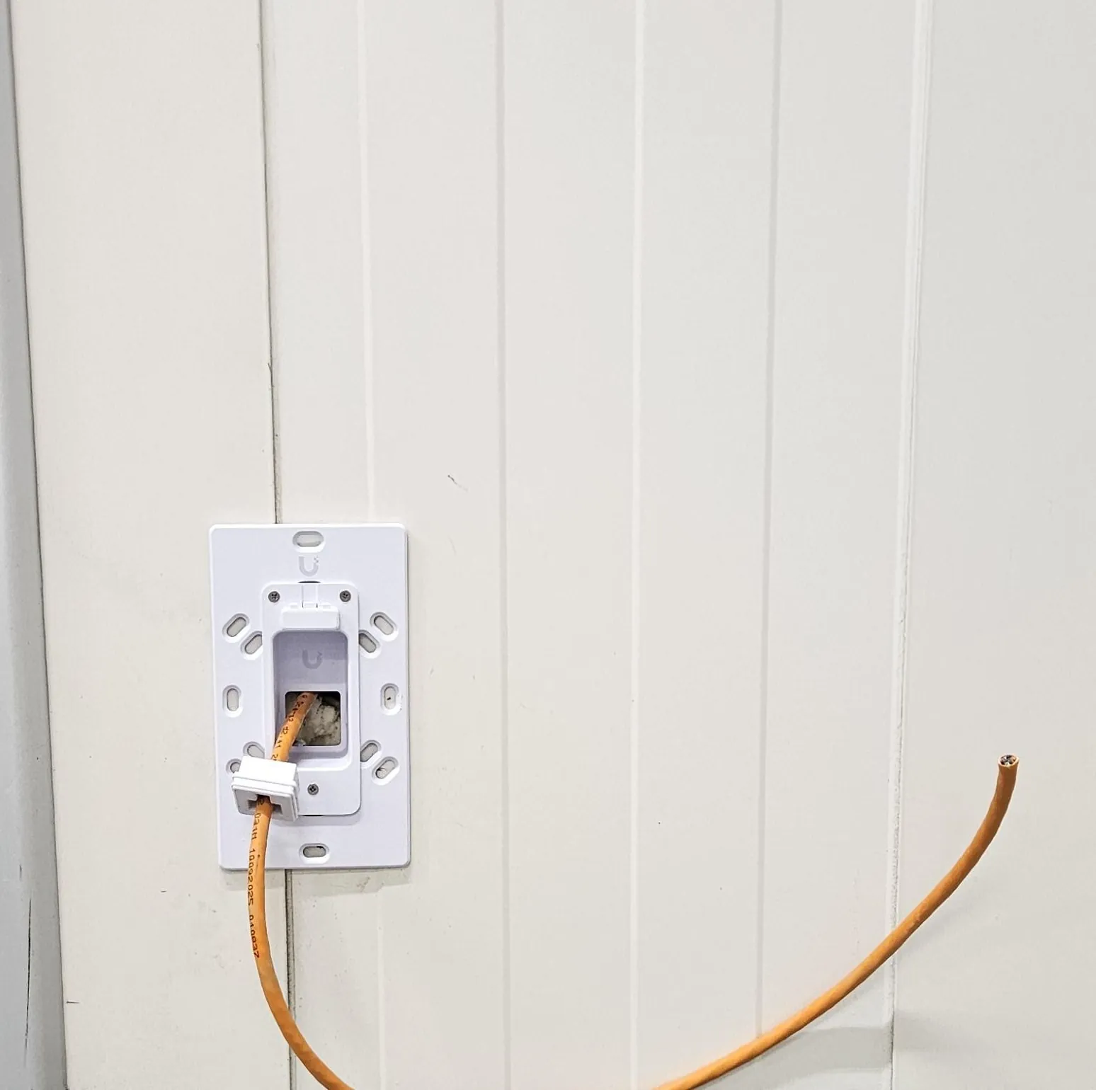 Inbouwplaat voor een UniFi-lezer, de oranje kabel komt er nog los uit