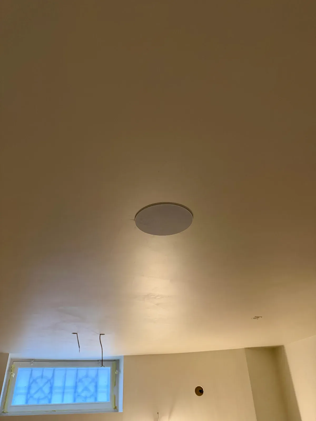 Witte inbouwspeaker strak in het afgewerkte plafond van de woning in Amsterdam