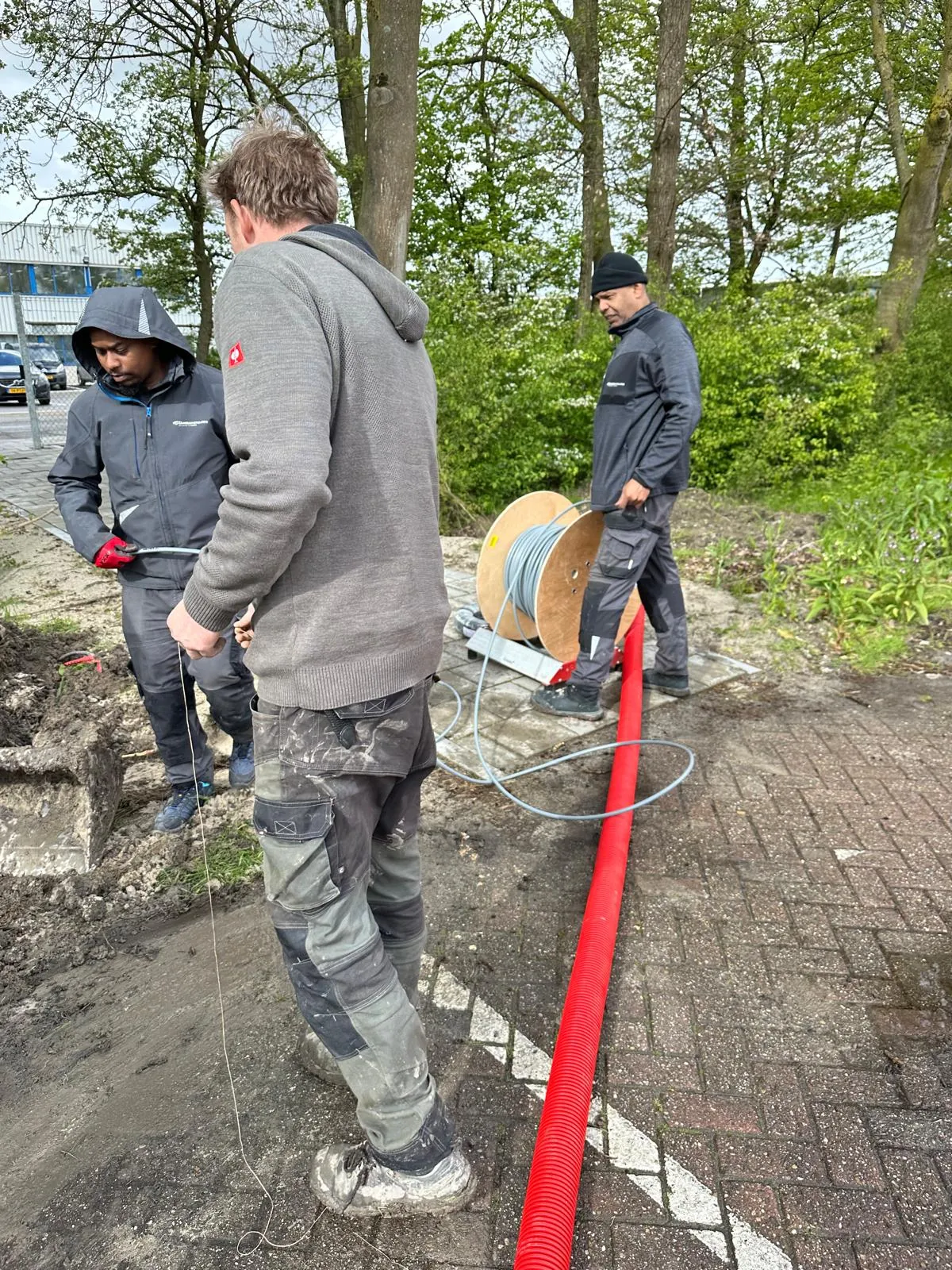 Drie monteurs rollen kabel af van een haspel bij het hotel in Bergen