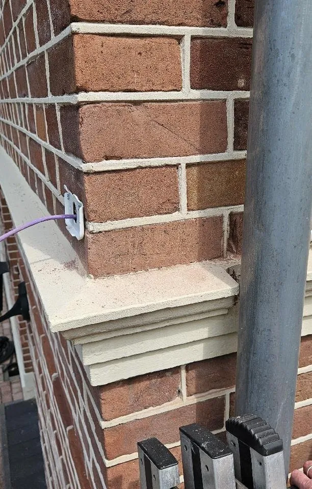 Kabel gaat door een klein gat in het metselwerk net boven de raamdorpel